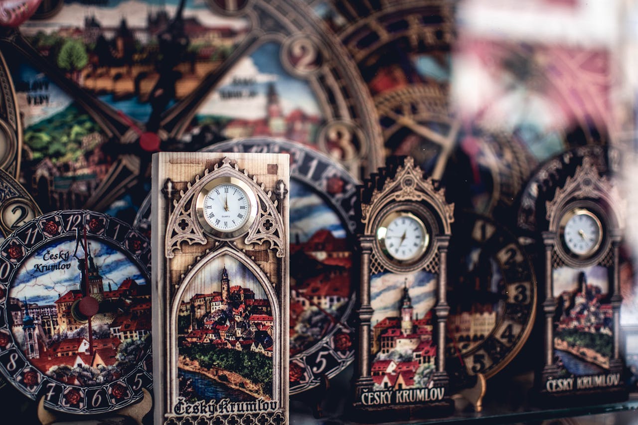 Detailed shot of ornate clocks featuring Český Krumlov landscapes, rich in design and decoration.